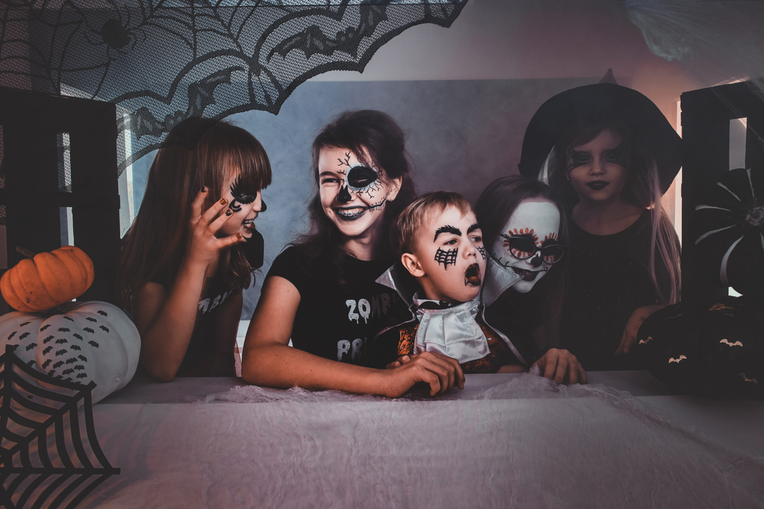 Happy kids in creepy Halloween costumes and makeup enjoying their little party.